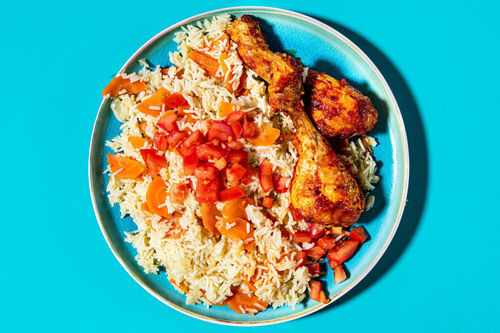 Feuriges Harissa-Hähnchen aus dem Ofen auf Gemüsereis mit frischen Tomaten