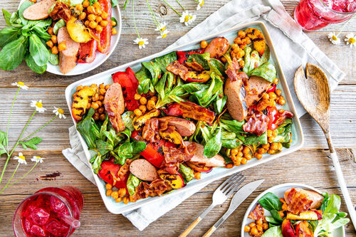 BBQ-Special: Geflügelwurst mit Bacon auf buntem Grillsalat mit Kichererbsen