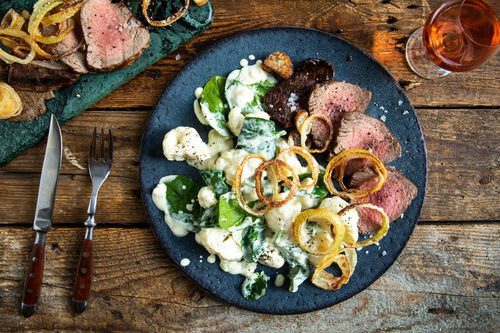 Deftiges Rindersteak mit Röstzwiebeln auf cremigem Blumenkohl mit Spinat