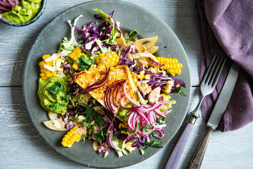 Gebackener Feta und frischer Mais auf buntem Salat mit Guacamole
