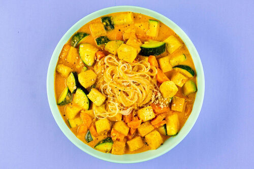 Curry-Erdnuss-Suppe mit gebratenem Tofu mit buntem Gemüse und Glasnudeln