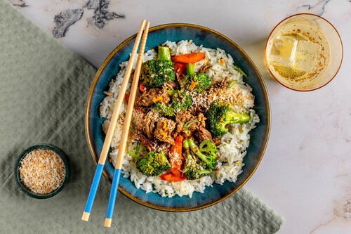 Brokkoli-Bio-Hack-Pfanne mit Orange garniert mit Kokosraspel, dazu Reis