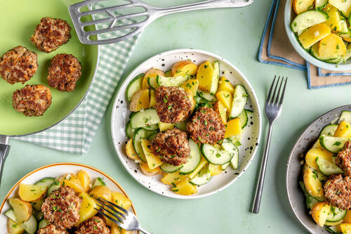 Gem. Hackbällchen auf warmem Kartoffelsalat mit frischer Gurke und Petersilie