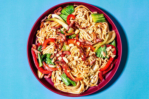 Udon-Nudeln mit Speck und Gemüse in Sweet-Chili-Sauce garniert mit Erdnüssen