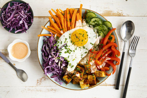 Bunte Bowl mit Spiegelei und Tofu auf Sushireis mit Gemüse und Sriracha-Mayo