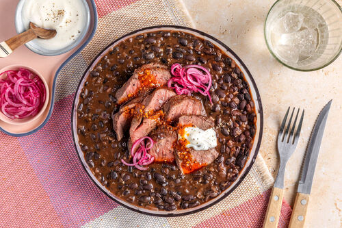Rindersteak auf Bohneneintopf mit eingelegten Zwiebeln und Joghurt