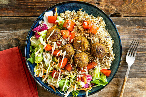 Extraviele Falafeln mit Tahinisauce auf Perlencouscous und Salat