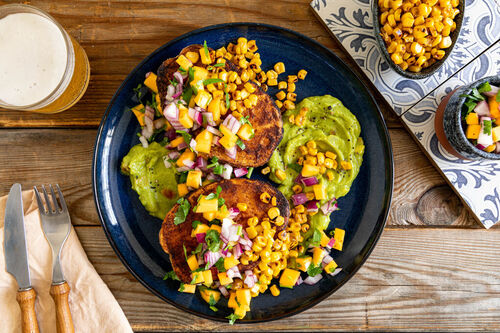 Süßkartoffeln mexikanische Art mit Kaki-Salsa und geröstetem Mais, serviert auf Guacamole