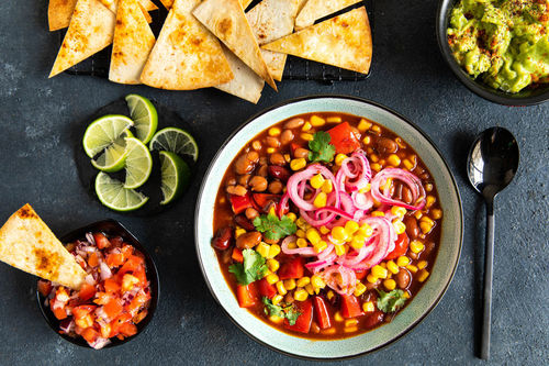 Bohnen-Mais-Chili mit Guacamole mit eingelegten Zwiebeln und Tortillachips