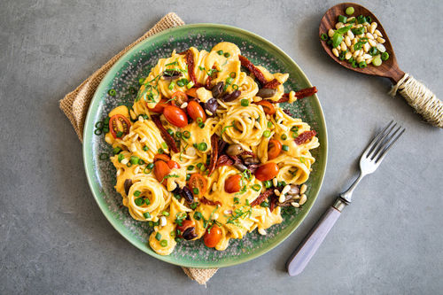 Pasta mit Pinienkernen und Oliven in veganer Karottencreme mit Tomaten