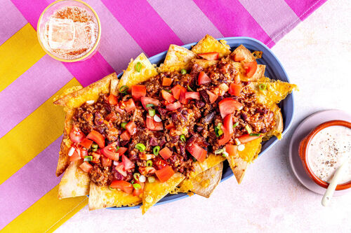 Käse-Nachos mit Chili con Carne garniert mit Lauchzwiebeln und Tomaten