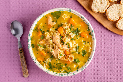 Vegane Hühnersuppe mit Bio-„Bauernhof“-Pasta mit buntem Gemüse, dazu Baguettescheiben