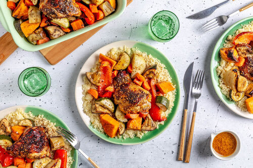 Geröstete Hähnchenoberkeulen auf Ofengemüse serviert mit Couscous