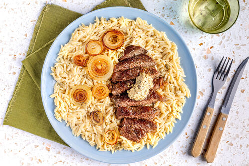 „Planted“-Steak mit Kapernbutter mit karamellisierten Zwiebeln auf Käse-Risoni
