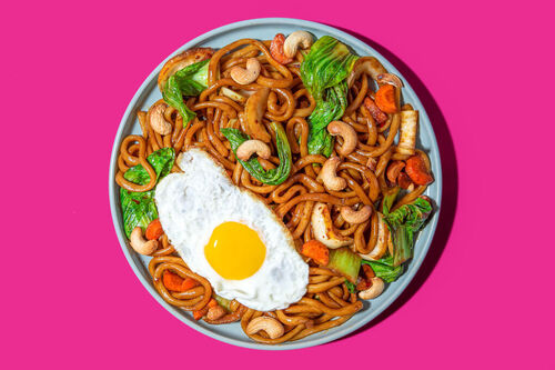Udon-Nudeln mit Spiegelei und Gemüse in pikanter Sauce garniert mit Cashews