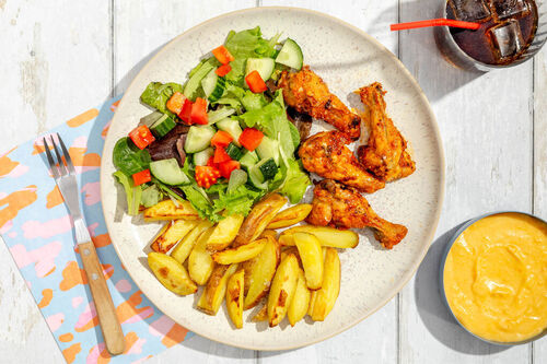 RS Drumsticks Buffalo-Style mit Cheddarsauce dazu Ofenpommes und Tomaten-Gurken-Salat