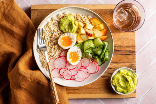 Fruchtige Reis-Bowl mit Apfel und Ei mit Radieschen, Gurke und Guacamole