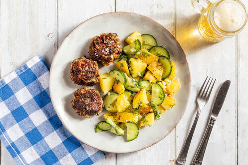 Fleischbällchen auf warmem Kartoffelsalat mit frischen Gurken und Petersilie