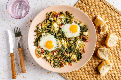 Grüne Feta-Spinat-Shakshuka serviert mit knusprigem Baguette
