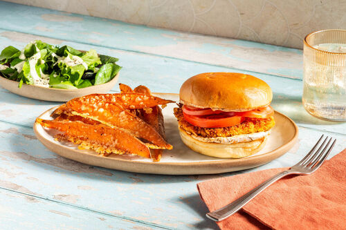 Burger mit Veggie-„Hähnchen“ und Tomate dazu Süßkartoffelpommes mit Käse und Salat