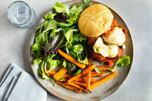 Veggie-Burger mit „Hackbällchen“ und Käse, dazu Karottenpommes und Salat