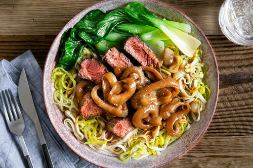Philippinisches Rindersteak mit Nudeln dazu Röstzwiebeln in Sauce und Pak Choi