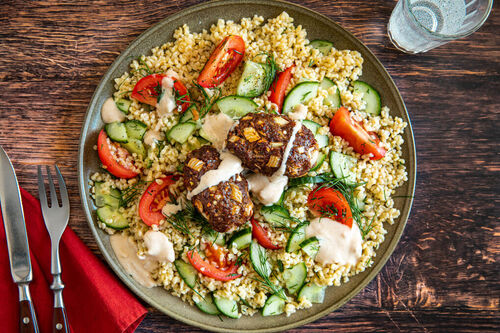 Hackröllchen Kofta-Art mit Tahinisauce auf Bulgursalat mit Gurke und Tomate