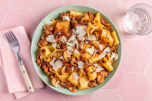 Pappardelle mit Champignon-Bolognese garniert mit gerösteten Zwiebeln und Käse