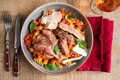 Rindersteak mit gehobeltem Käse auf Pasta mit Tomatensauce