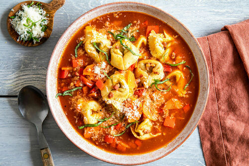 Tomatensuppe mit Tortelloni und Speck garniert mit Basilikum und Käse