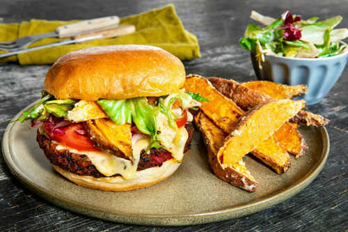 Tex-Mex-Burger mit Bohnen-Käse-Patty und buntem Salat, dazu Süßkartoffelpommes