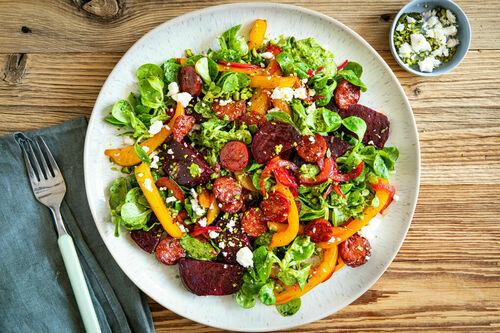 Kross gebratene Chorizo und Feta auf buntem Salat mit Pistaziendressing