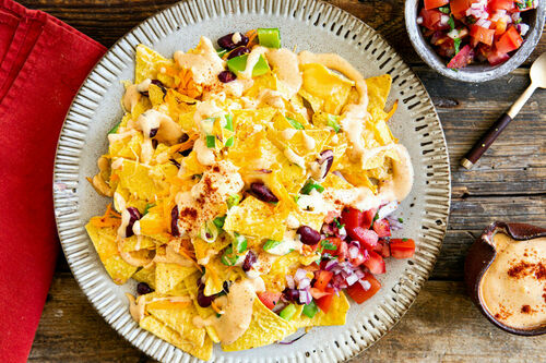 Nachos mit Bohnen und Gemüse garniert mit Käsesauce und Salsa